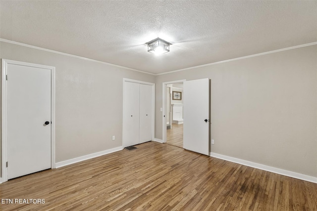 spare room with hardwood / wood-style floors, ornamental molding, and a textured ceiling