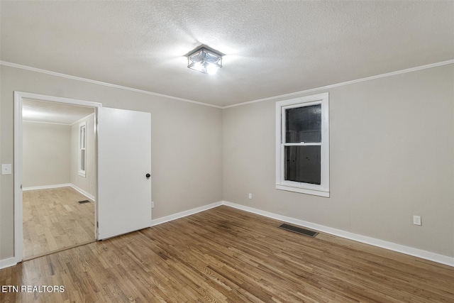 empty room featuring wood-type flooring, a textured ceiling, and ornamental molding