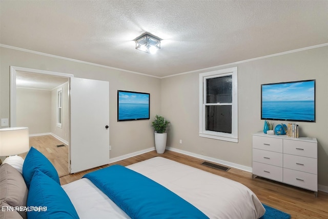 bedroom with a textured ceiling, light wood-type flooring, and ornamental molding