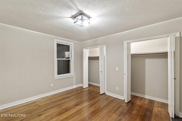 unfurnished bedroom featuring crown molding, a closet, dark wood-type flooring, and a textured ceiling