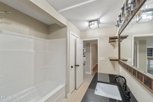 bathroom with tile patterned floors, vanity,  shower combination, and a textured ceiling