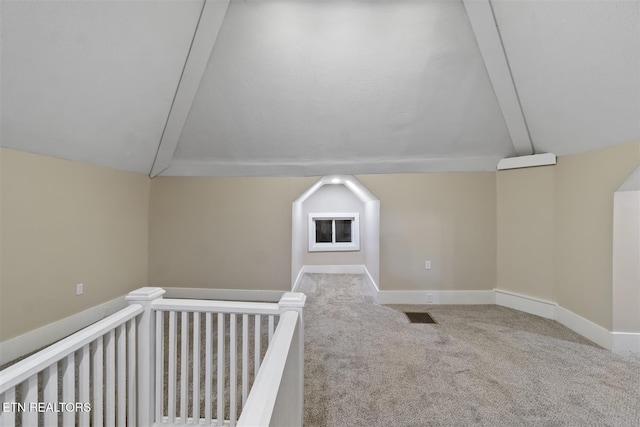 additional living space with light carpet and vaulted ceiling with beams