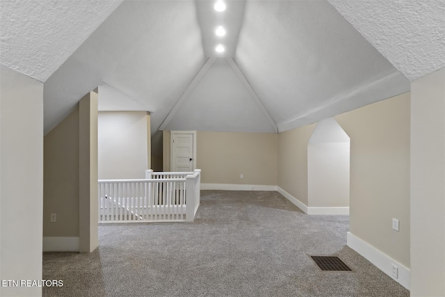 bonus room with a textured ceiling, carpet floors, and vaulted ceiling