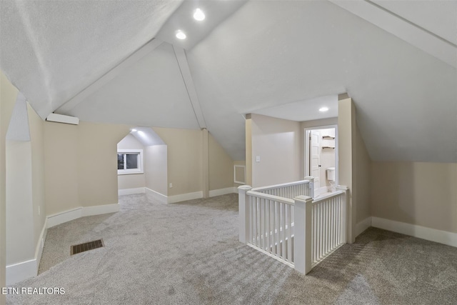 additional living space with carpet flooring, a textured ceiling, and vaulted ceiling