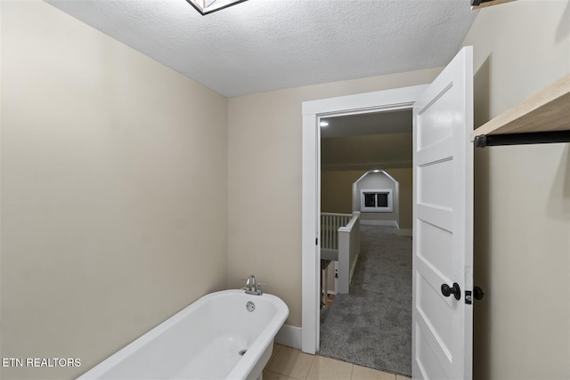 bathroom featuring a washtub, a textured ceiling, and tile patterned floors