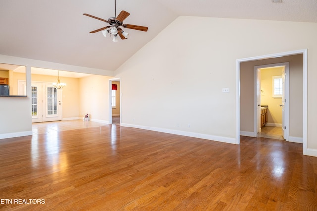 unfurnished living room with ceiling fan with notable chandelier, wood-type flooring, and high vaulted ceiling