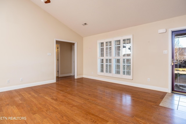 empty room featuring wood-type flooring and high vaulted ceiling