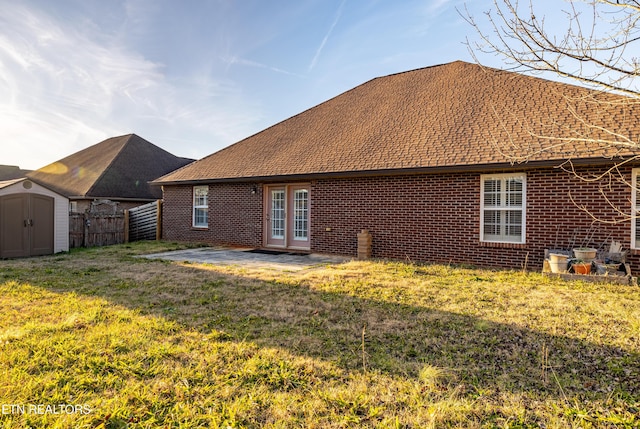 rear view of house featuring a yard, a patio area, and a storage shed