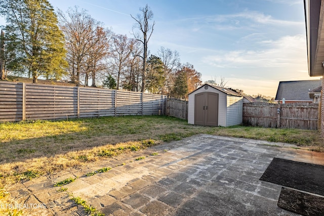 patio terrace at dusk featuring a storage unit and a yard