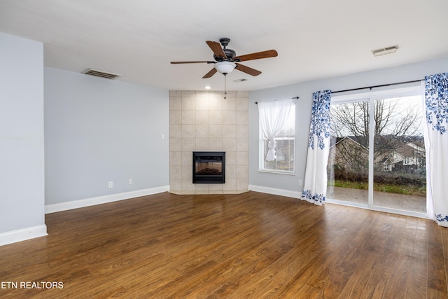 unfurnished living room featuring a tiled fireplace, ceiling fan, and dark hardwood / wood-style floors