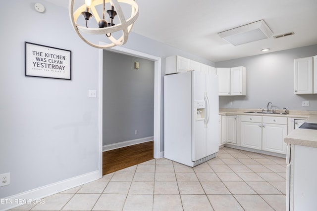 kitchen with an inviting chandelier, white cabinetry, white fridge with ice dispenser, and light tile patterned flooring