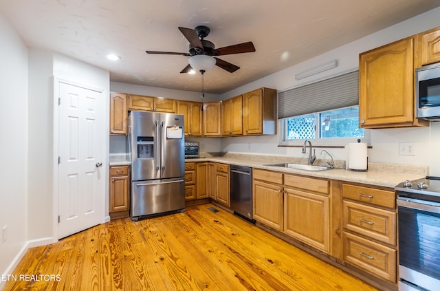 kitchen with ceiling fan, sink, stainless steel appliances, and light wood-type flooring