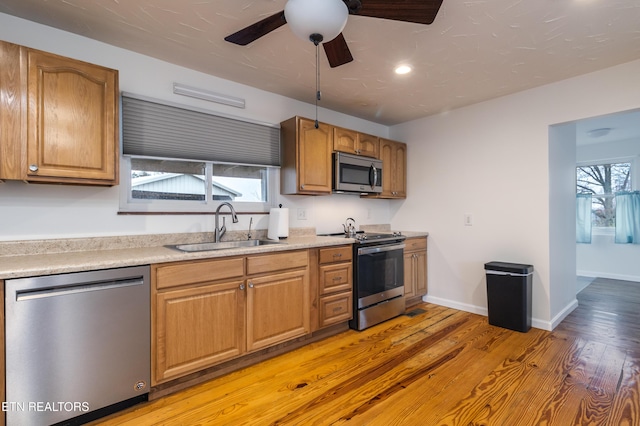 kitchen featuring ceiling fan, sink, stainless steel appliances, and light hardwood / wood-style flooring