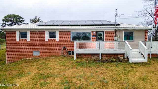 rear view of house featuring a yard, a deck, and solar panels