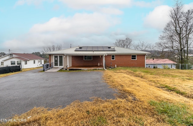 rear view of property with a yard and solar panels