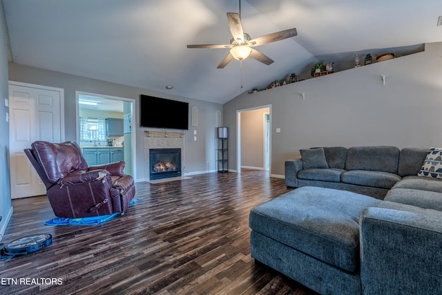 living room featuring ceiling fan, sink, dark wood-type flooring, lofted ceiling, and a tiled fireplace