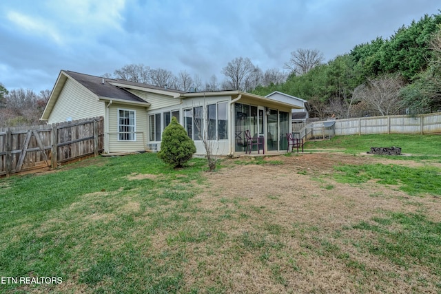 rear view of property featuring a sunroom and a yard