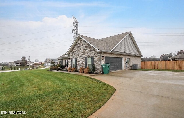 view of front of property with a garage, a front yard, and central AC