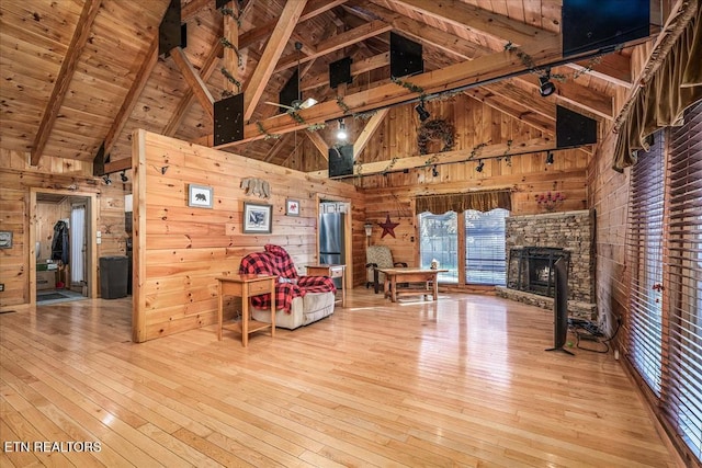 unfurnished living room with hardwood / wood-style flooring, wooden walls, beam ceiling, and high vaulted ceiling