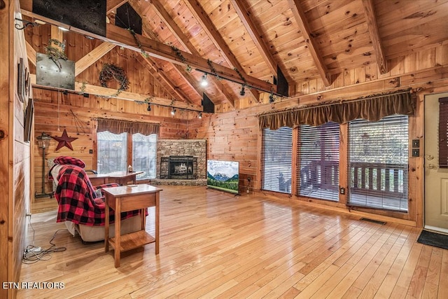 unfurnished living room featuring beam ceiling, wooden ceiling, high vaulted ceiling, wood walls, and light hardwood / wood-style floors