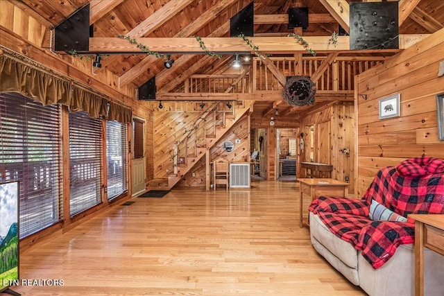 living room with beam ceiling, wooden walls, wood ceiling, and light wood-type flooring