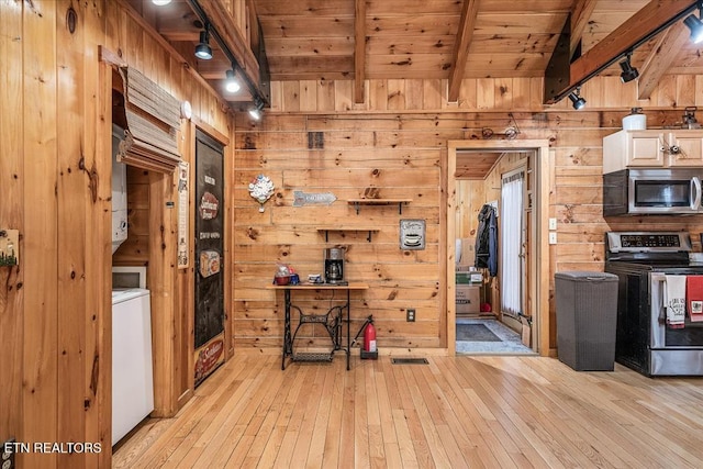 kitchen with wooden walls, appliances with stainless steel finishes, and light hardwood / wood-style flooring