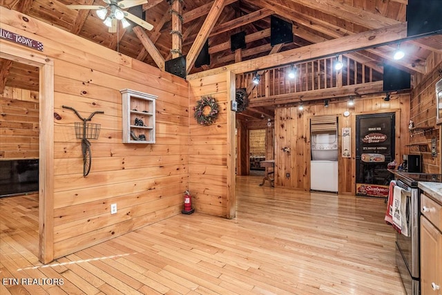 kitchen featuring wood walls, high vaulted ceiling, light hardwood / wood-style floors, and stainless steel range with electric stovetop