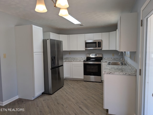 kitchen with white cabinets, light hardwood / wood-style floors, sink, and stainless steel appliances