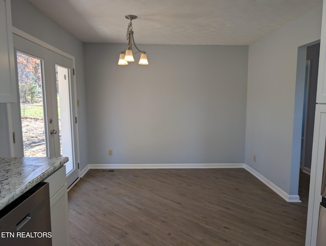 unfurnished dining area with dark hardwood / wood-style flooring and an inviting chandelier