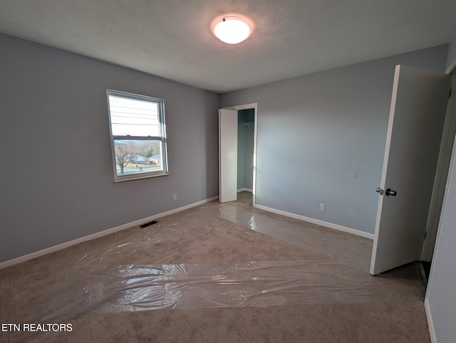 carpeted empty room featuring a textured ceiling