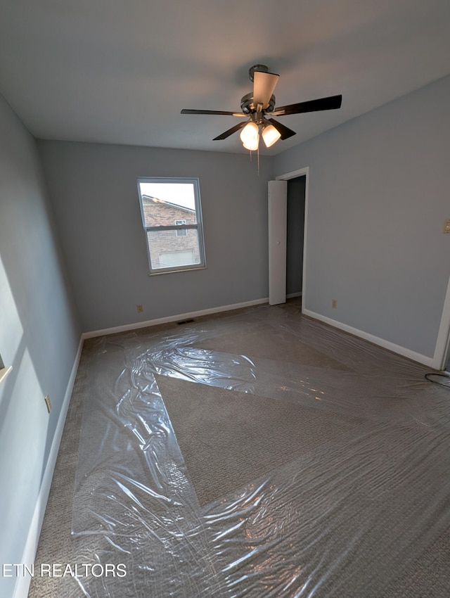 unfurnished room featuring ceiling fan and dark carpet