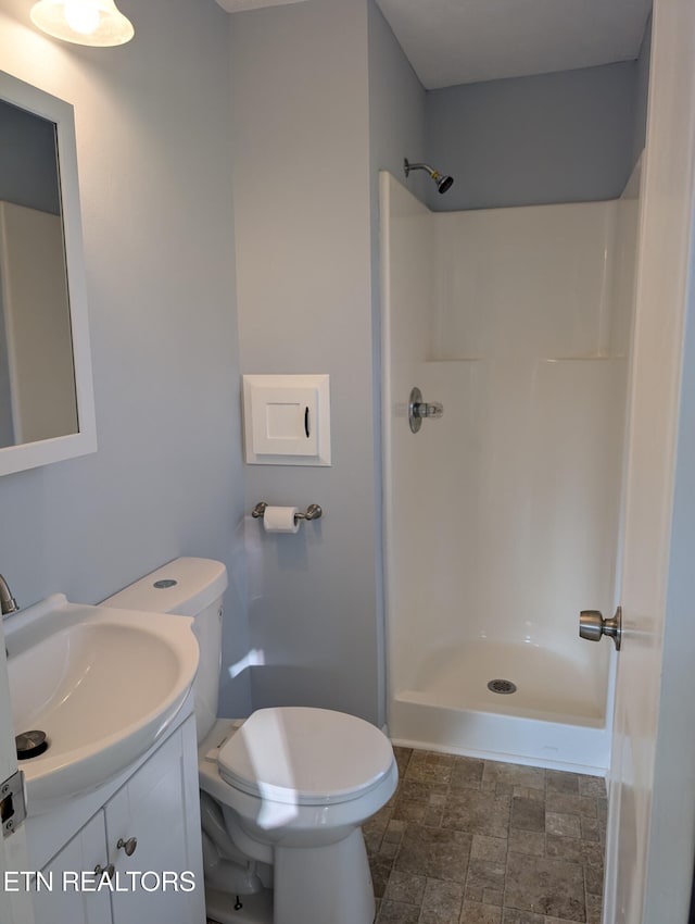 bathroom featuring toilet, vanity, and walk in shower