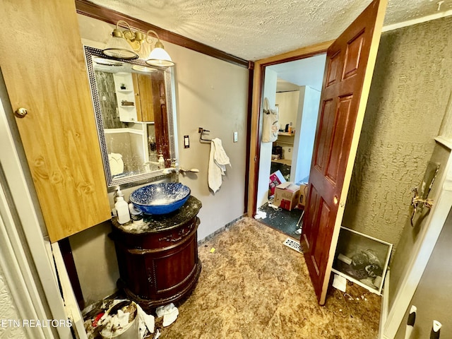 bathroom with a textured ceiling, vanity, and ornamental molding