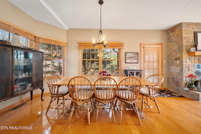 dining room with wood-type flooring, a textured ceiling, a wealth of natural light, and an inviting chandelier