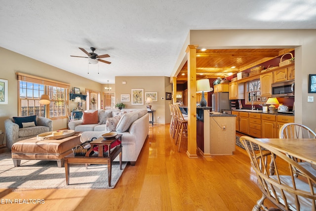 living room with beamed ceiling, ceiling fan, a textured ceiling, and light hardwood / wood-style flooring