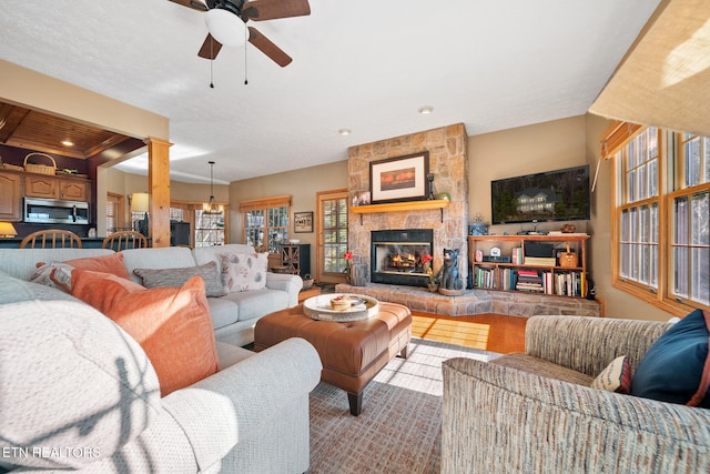 living room featuring a fireplace, beam ceiling, light hardwood / wood-style flooring, and ceiling fan