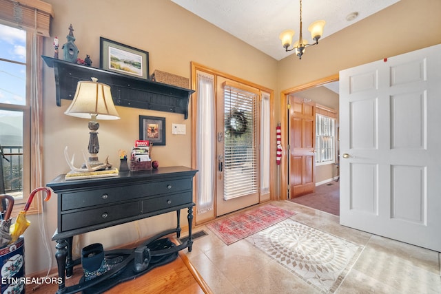 foyer featuring tile patterned flooring, a textured ceiling, and an inviting chandelier