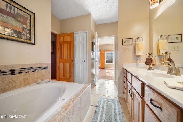 bathroom featuring tiled tub, tile patterned flooring, vanity, and a textured ceiling