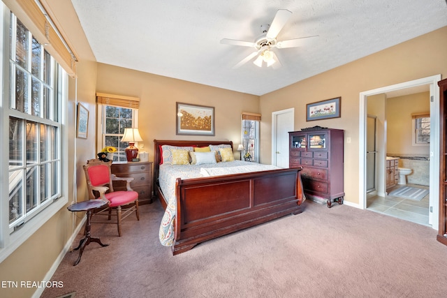 bedroom featuring a textured ceiling, light colored carpet, ceiling fan, and ensuite bathroom