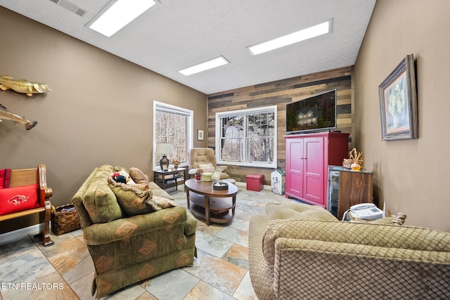 living room featuring a textured ceiling and wood walls