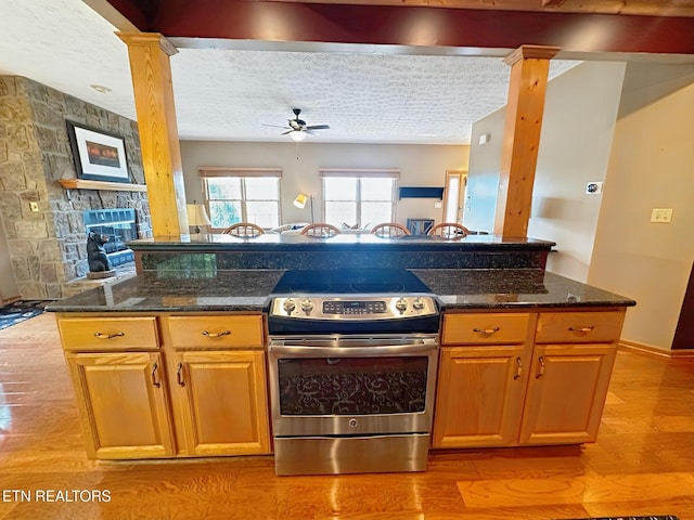 1132 E Foothills Dr, Gatlinburg, TN 37738 - kitchen with electric stove, ornate columns, ceiling fan, light wood-style floors, and dark stone countertops