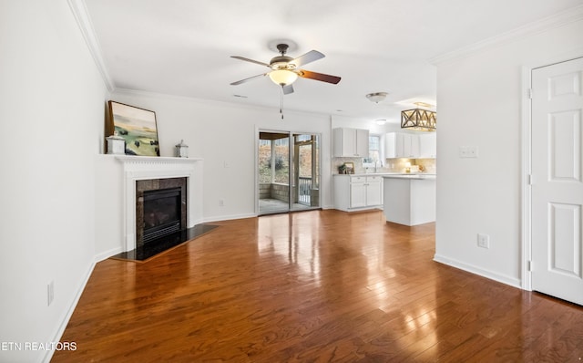 unfurnished living room with ceiling fan, crown molding, sink, and hardwood / wood-style flooring