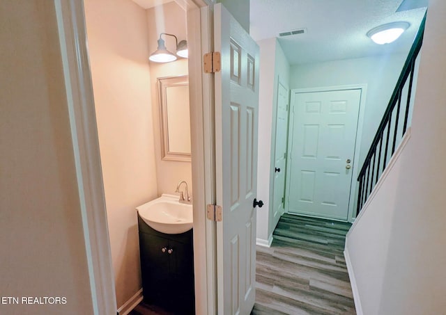 corridor featuring sink, hardwood / wood-style floors, and a textured ceiling