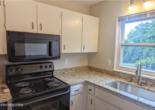 kitchen with black appliances, light stone counters, white cabinets, and sink