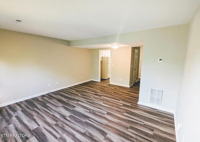 unfurnished room with a textured ceiling and dark hardwood / wood-style floors