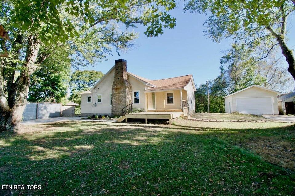 rear view of house featuring a yard, a garage, and an outdoor structure