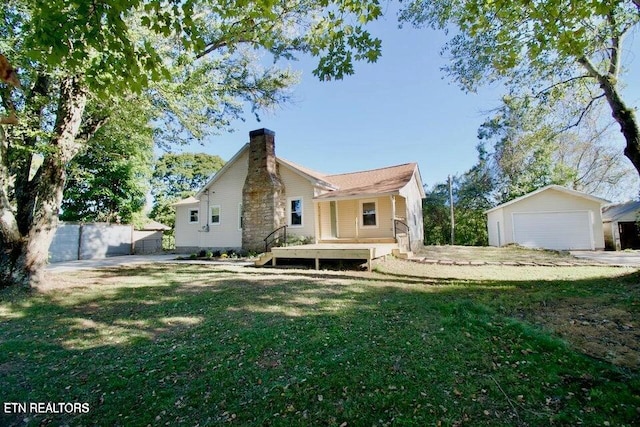 rear view of house featuring a yard, a garage, and an outdoor structure