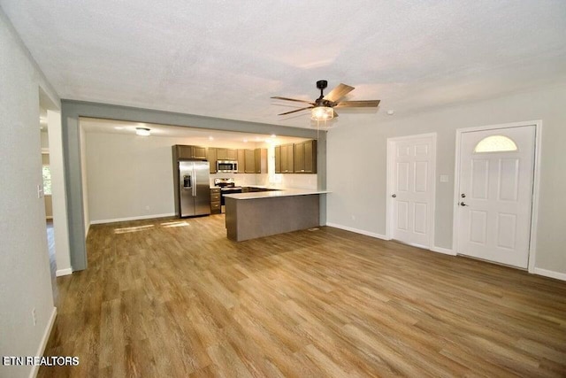 kitchen with kitchen peninsula, appliances with stainless steel finishes, a textured ceiling, and wood-type flooring