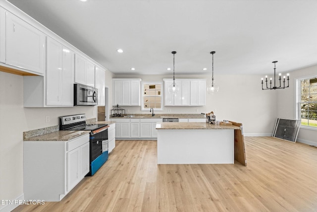 kitchen featuring white cabinets, light hardwood / wood-style floors, pendant lighting, a kitchen island, and appliances with stainless steel finishes