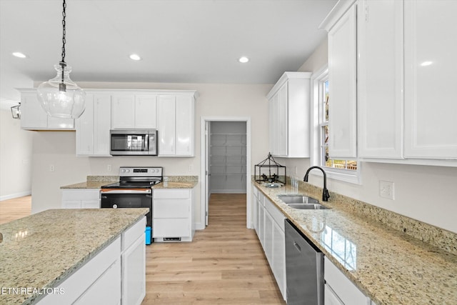 kitchen with white cabinets, sink, light hardwood / wood-style flooring, light stone countertops, and appliances with stainless steel finishes